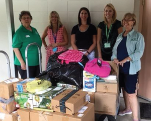 Chairs Marcy Edmondson & KarenSue Molis flanking school support staff with delivered supplies.